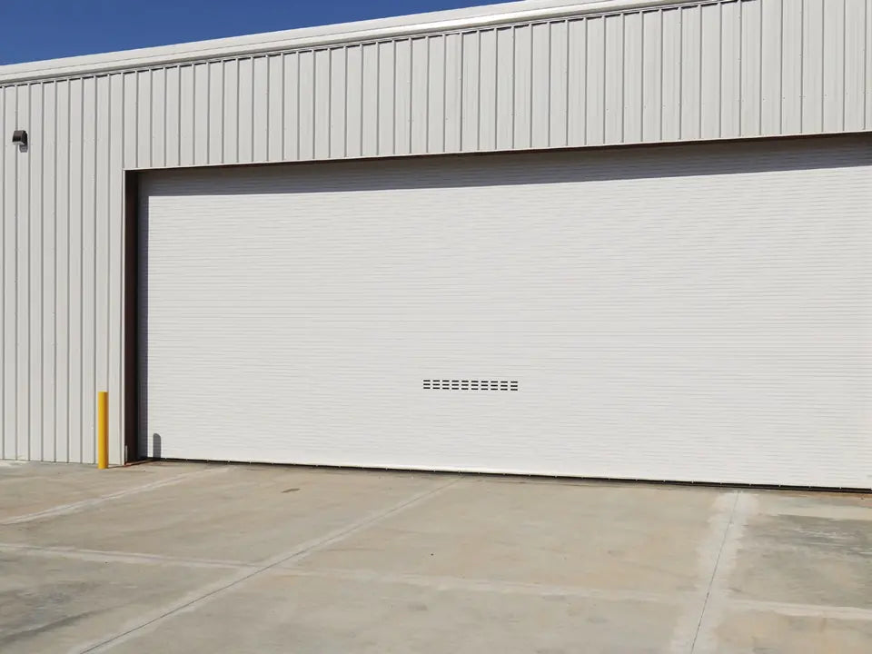 Wide ASTA 400 Series rolling service door on a metal industrial building